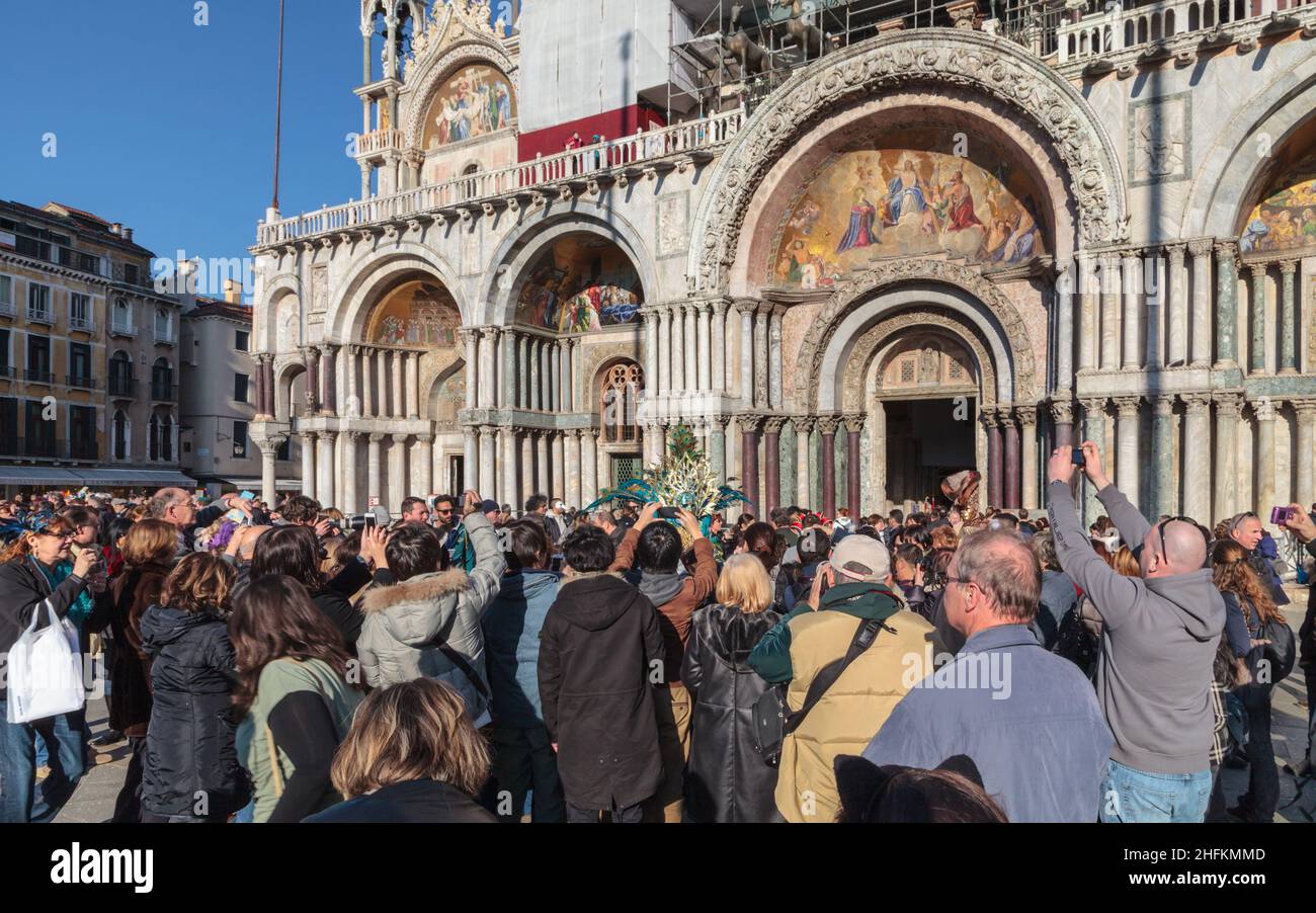 Photographers, tourists and visitors crowd around a participant in costume at the basilica on St Mark's Square, Venice Carnival, Italy Stock Photo