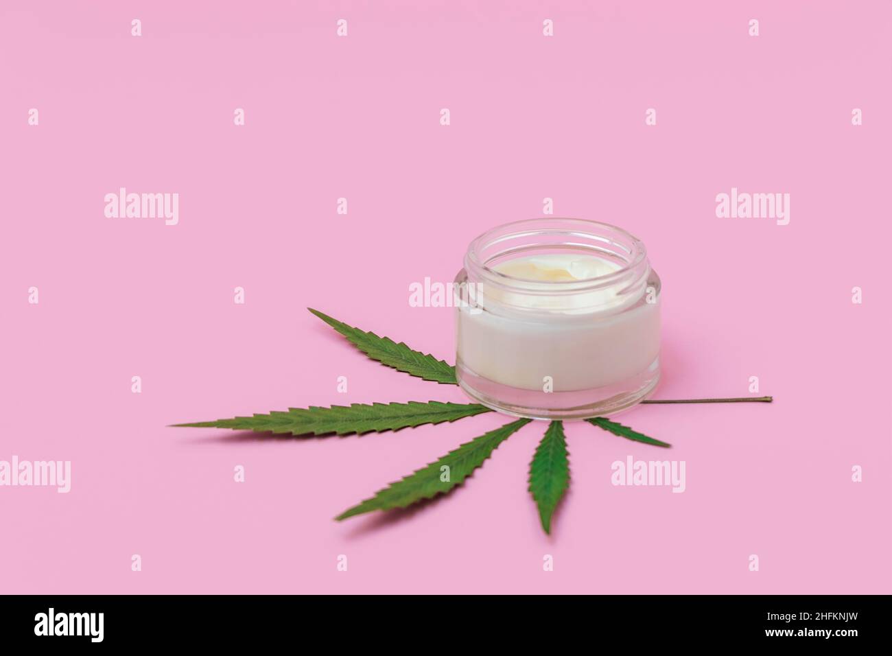 Cannabis hemp cream with marijuana leaf on soft pink background with copy space. Cannabis infused cosmetics concept Stock Photo