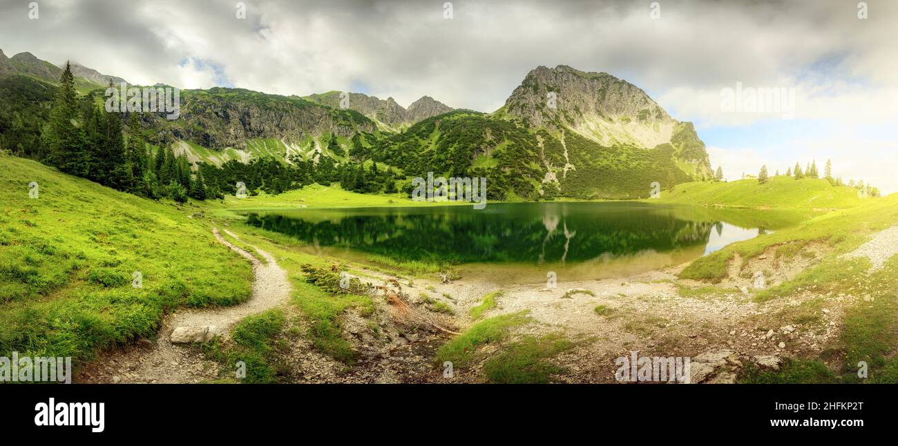 Panoramic scenery around a mountain lake with dramatic sunlight Stock Photo