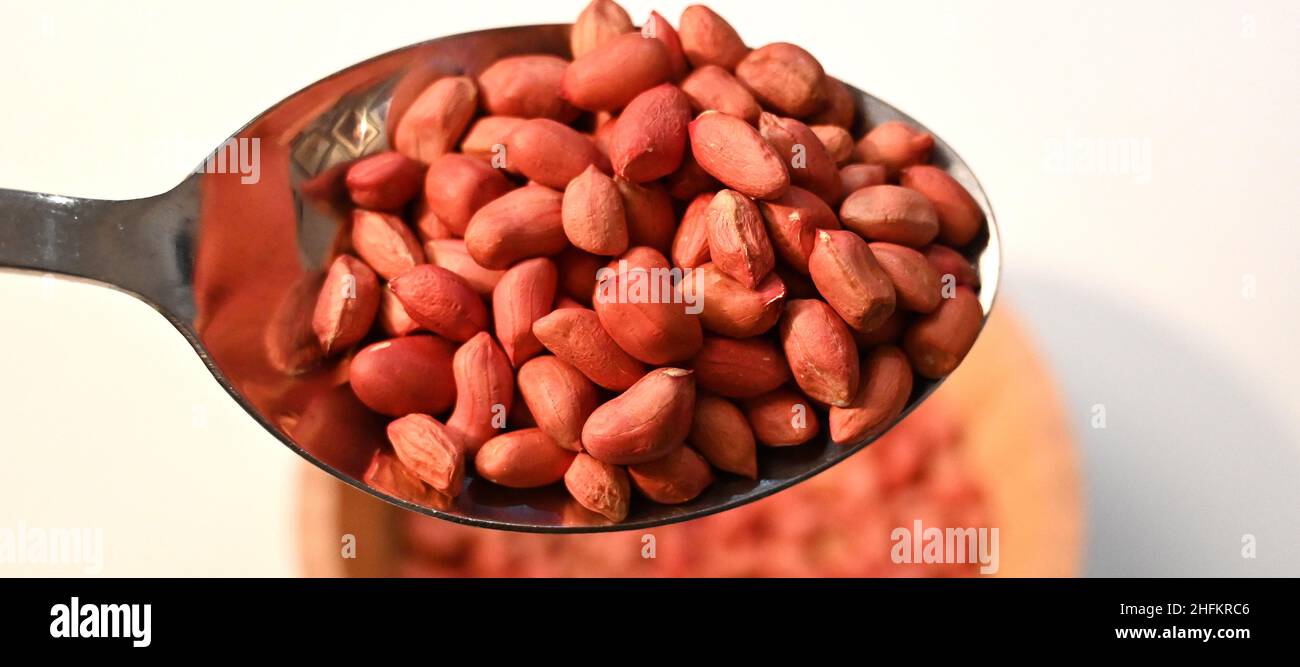 scoop of redskin peanuts from a bamboo bowl, Organic food store, Healthy eating Stock Photo