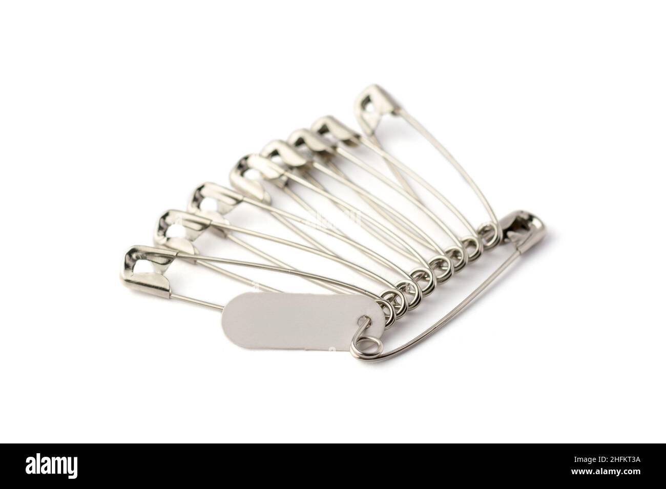 metal regular safety pins with empty tag, commonly used to fasten clothing, taken in shallow depth of field isolated in white background Stock Photo