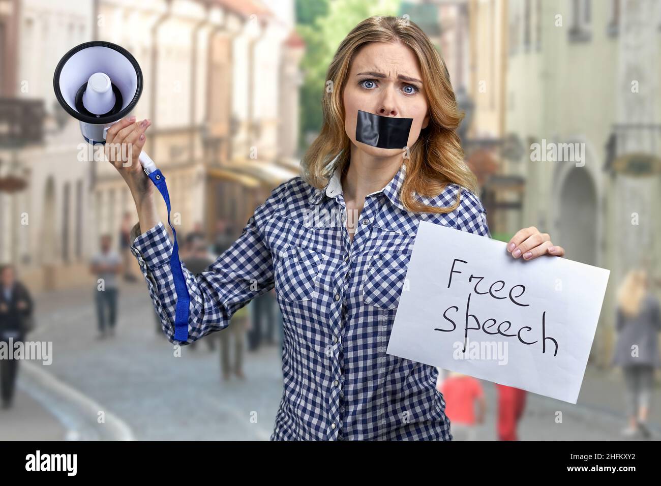 Woman protester with taped mouth holding banner with inscription Free speech. Stock Photo