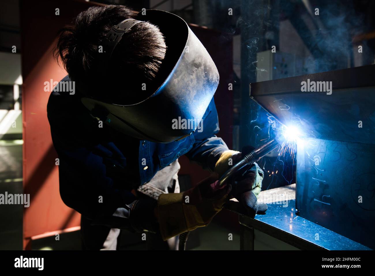 Welding works. Wire welding of Metal. Bright light and sparks. Worker in mask and gloves. Stock Photo