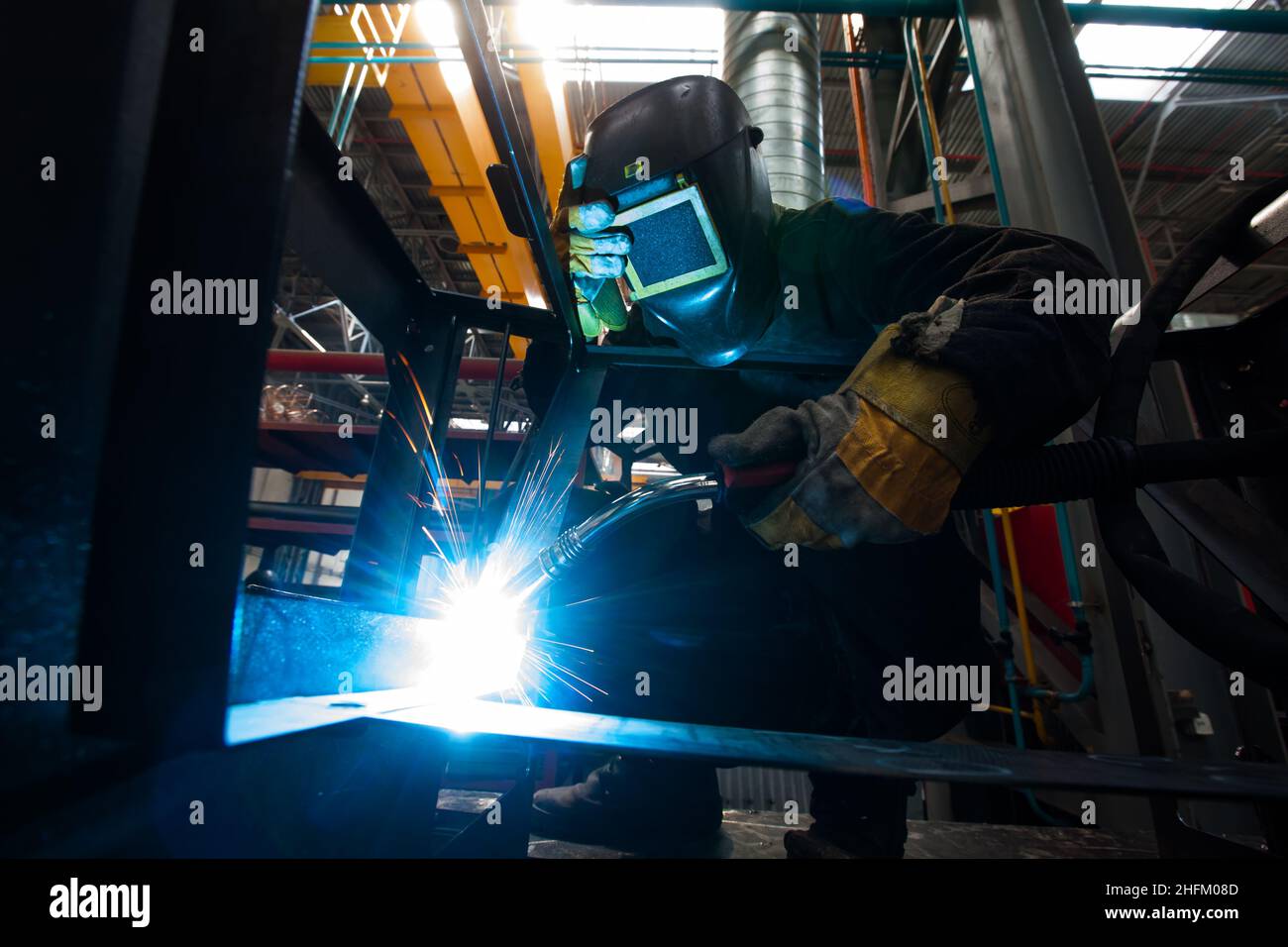 Welding works. Wire welding of Metal. Bright light and sparks. Worker in mask and gloves. Stock Photo
