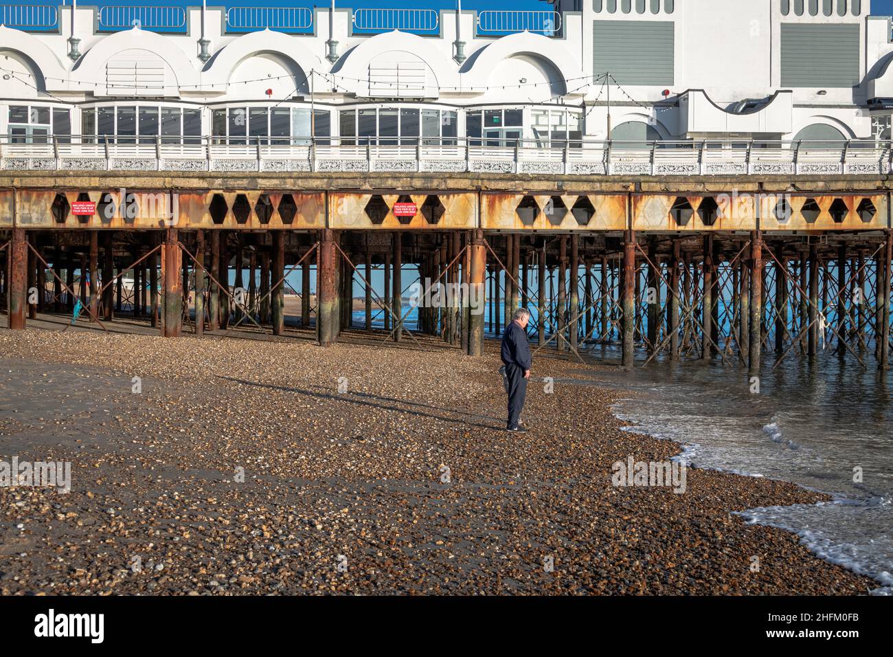 Man stands on Eastney Beach in front of South Parade Pier, Southport, Hampshire. Stock Photo