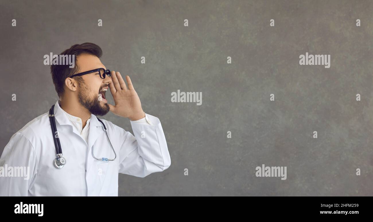 Doctor on copy space background shouting to draw attention to important healthcare news Stock Photo