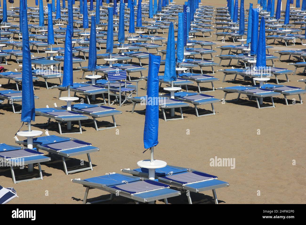 The detail of the beach loungers on the empty sandy beach. Showing lack of tourists and missing incomes for the hotels. Stock Photo
