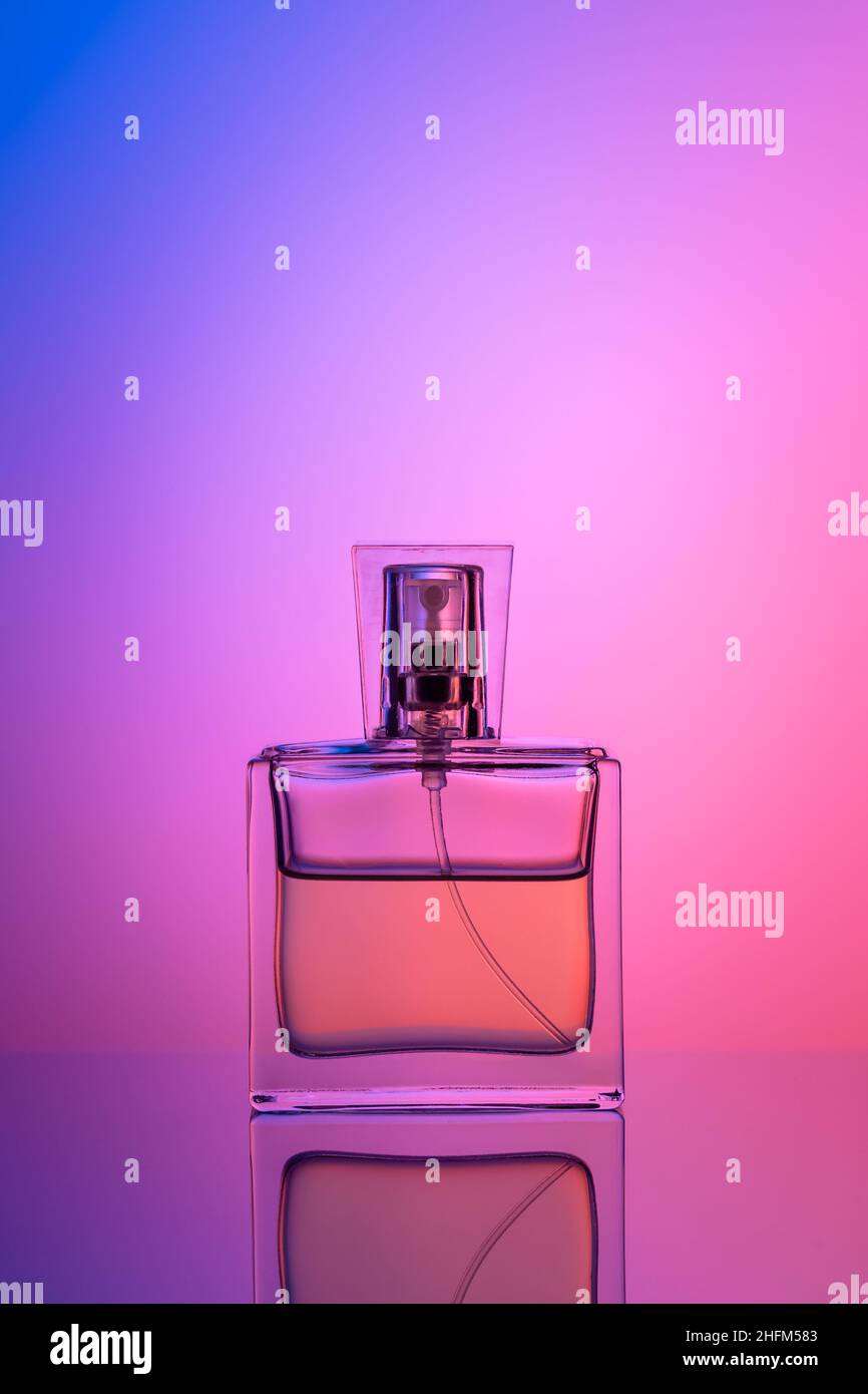 Bottle of perfume on purple neon background. Transparent silhouette, illuminated effect. Toilet water for women. Copy space for text Stock Photo