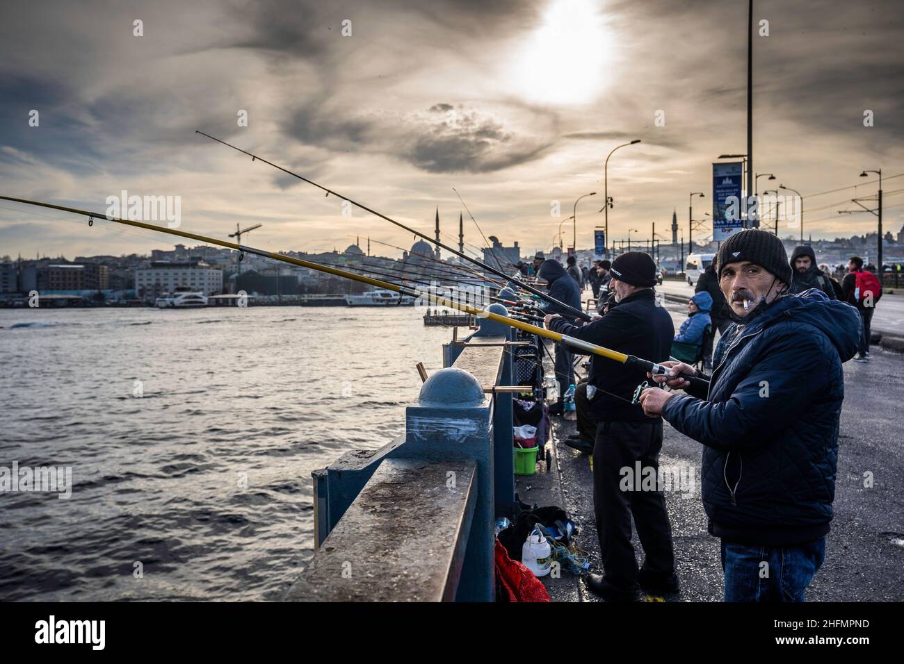 A man seen smoking a cigarette while fishing near the New Mosque (Yeni
