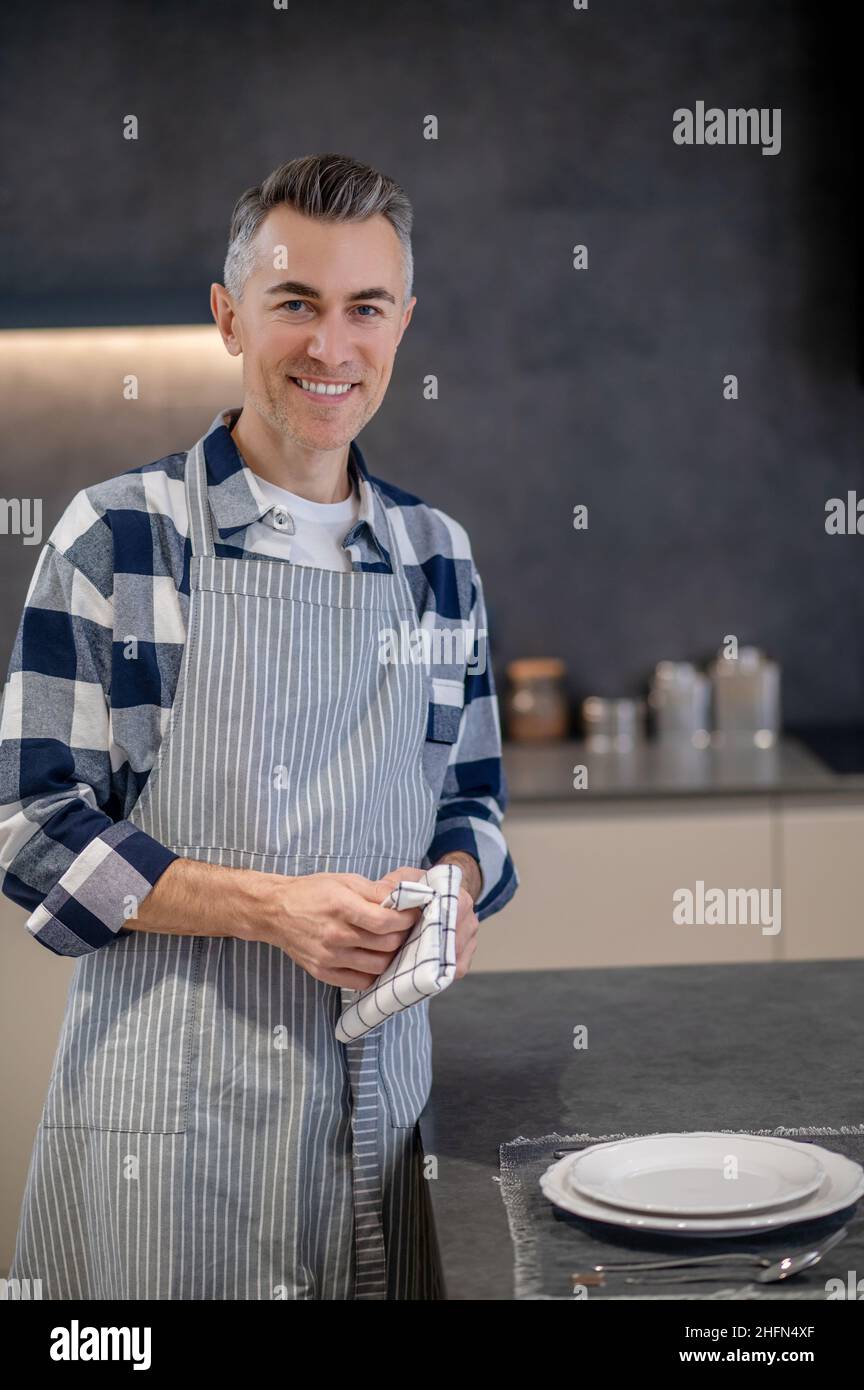 Happy man in apron with napkin looking at camera Stock Photo