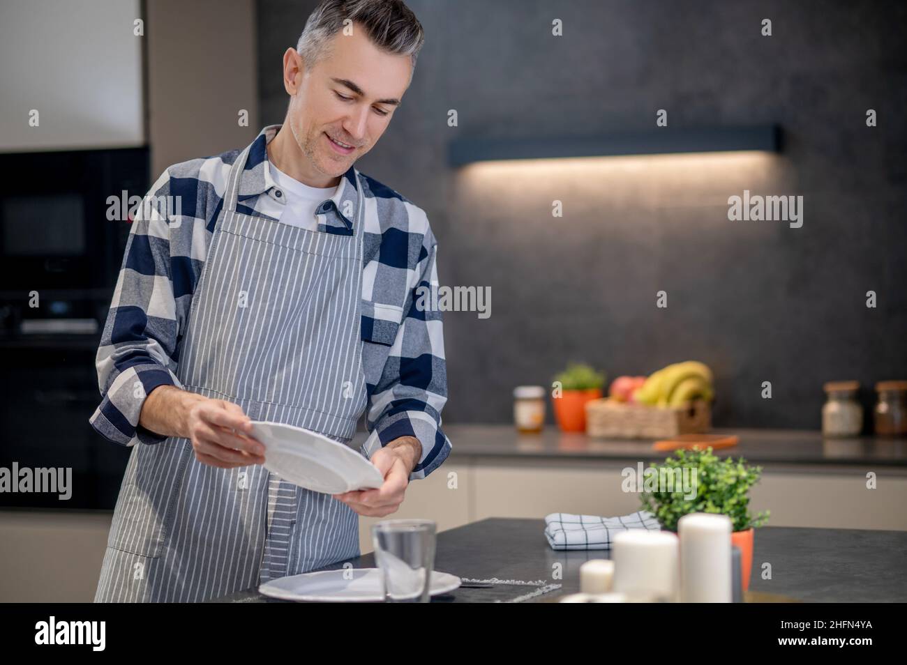 Man in apron examining plate in his hands Stock Photo