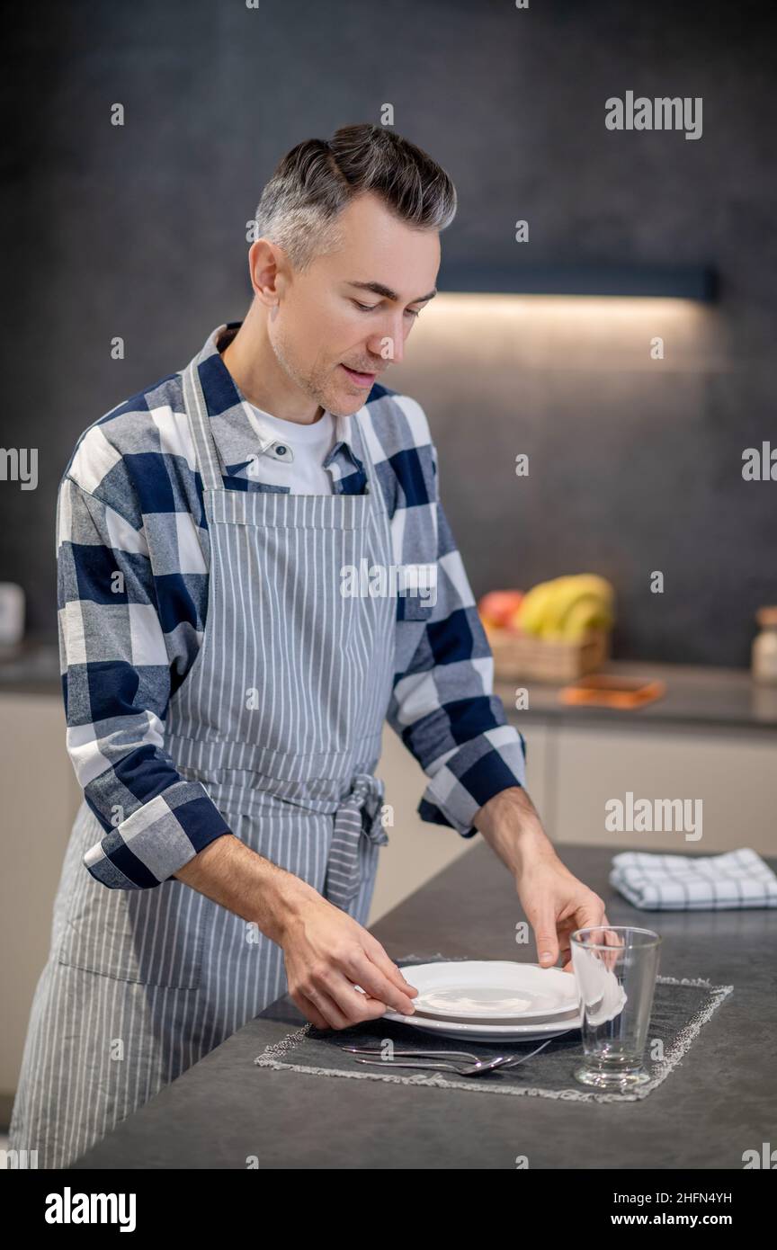 Man serving table neatly with clean tableware Stock Photo