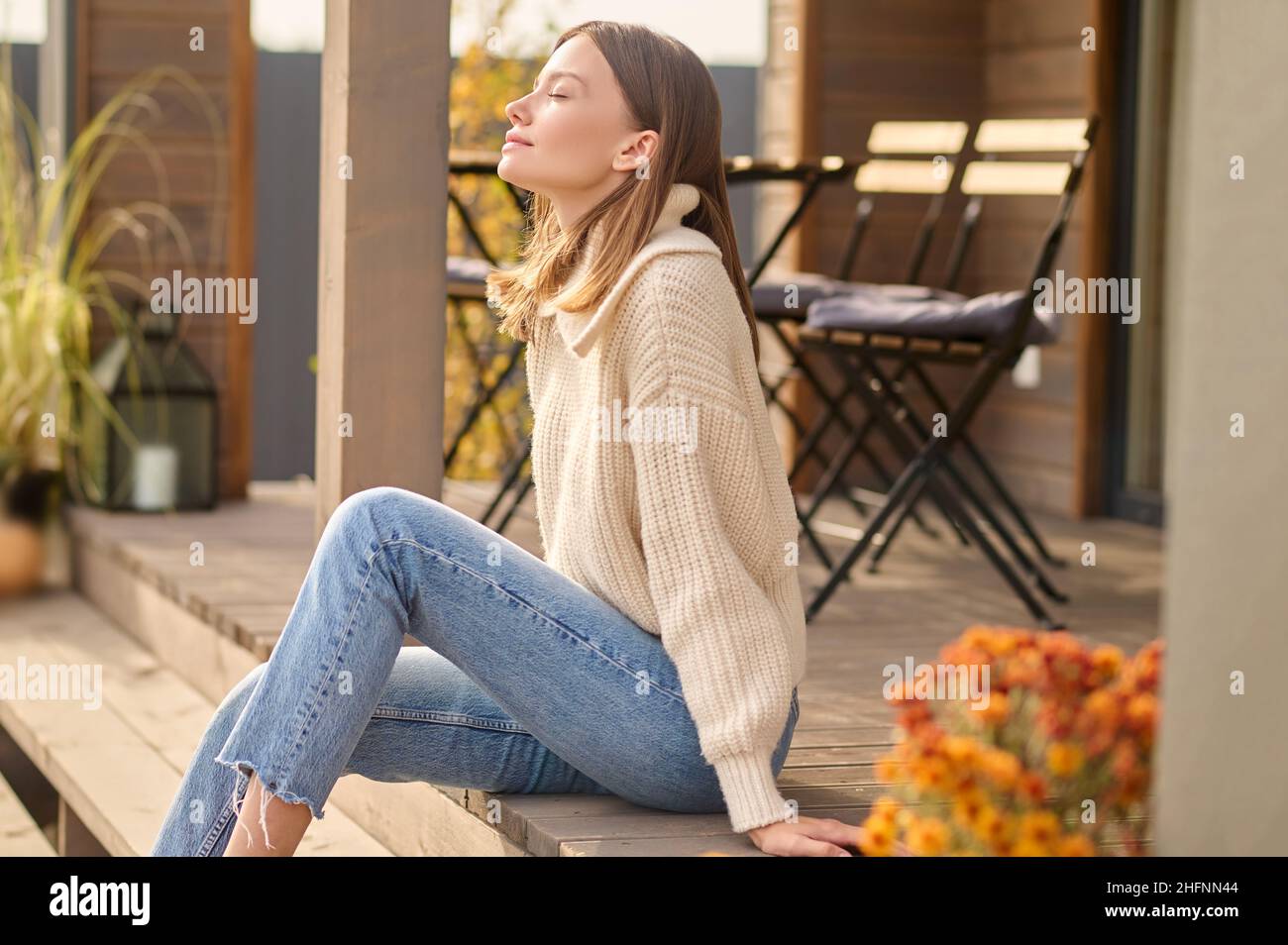 Woman with closed eyes sitting on porch of house Stock Photo - Alamy