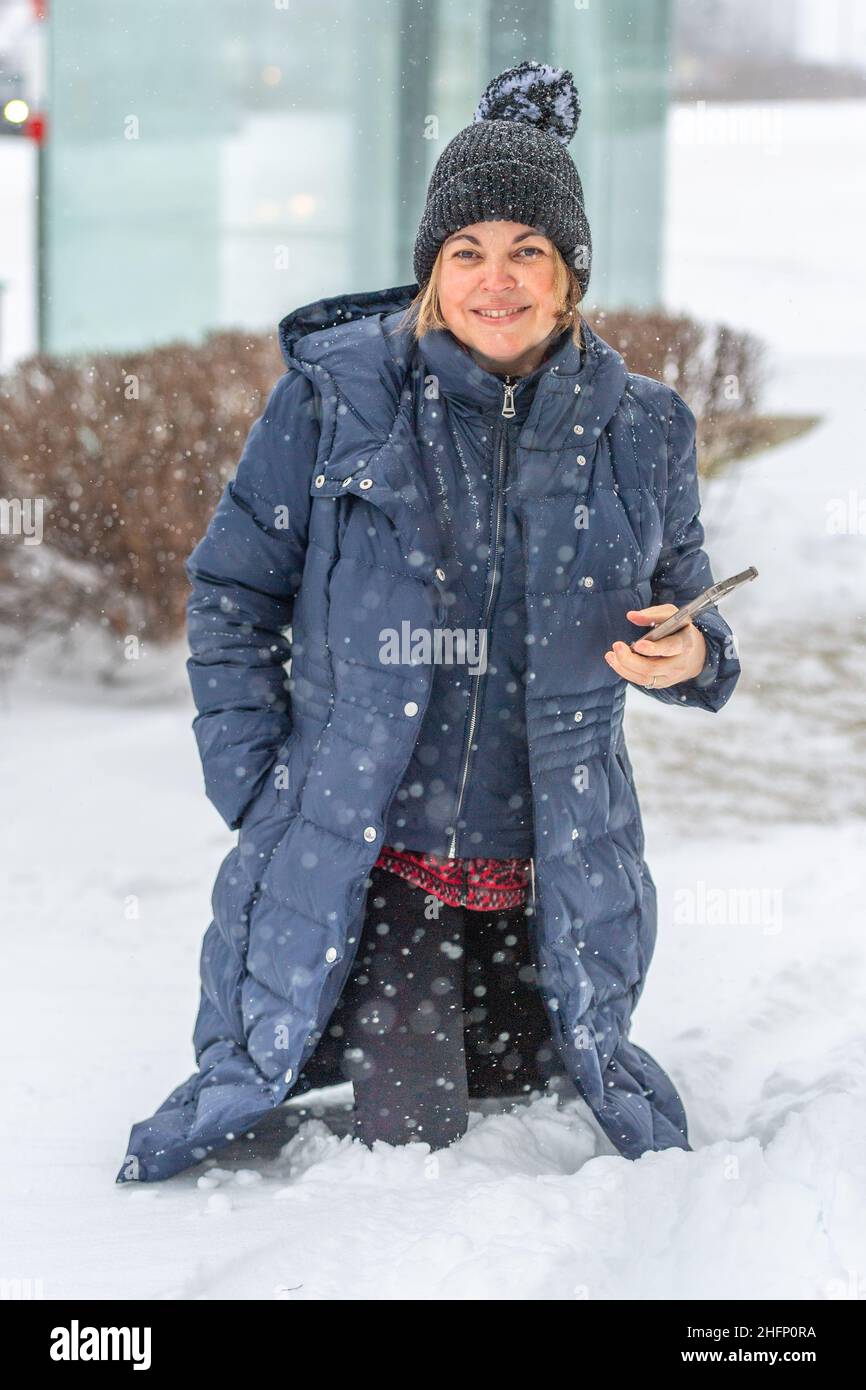 A Latin American woman walks by a bus stop where the snow is about the height of her knees. The winter snowstorm has caused many disruptions in Toront Stock Photo