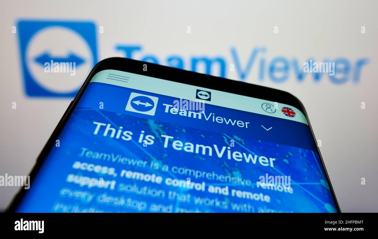 Mobile phone with webpage of German technology company TeamViewer AG on screen in front of business logo. Focus on top-left of phone display. Stock Photo