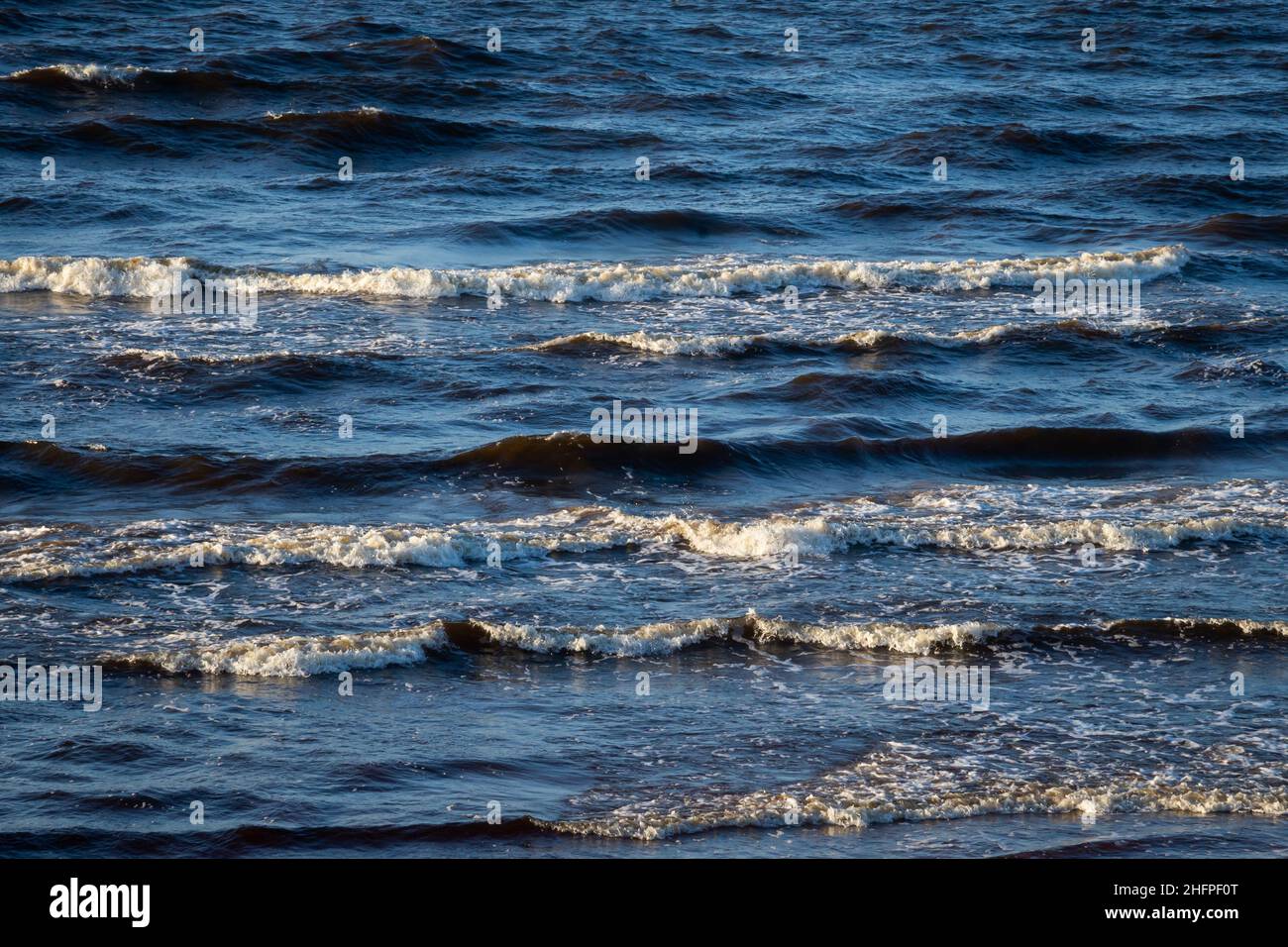 sea with white sand and blue water before storm. waves with white heads Stock Photo