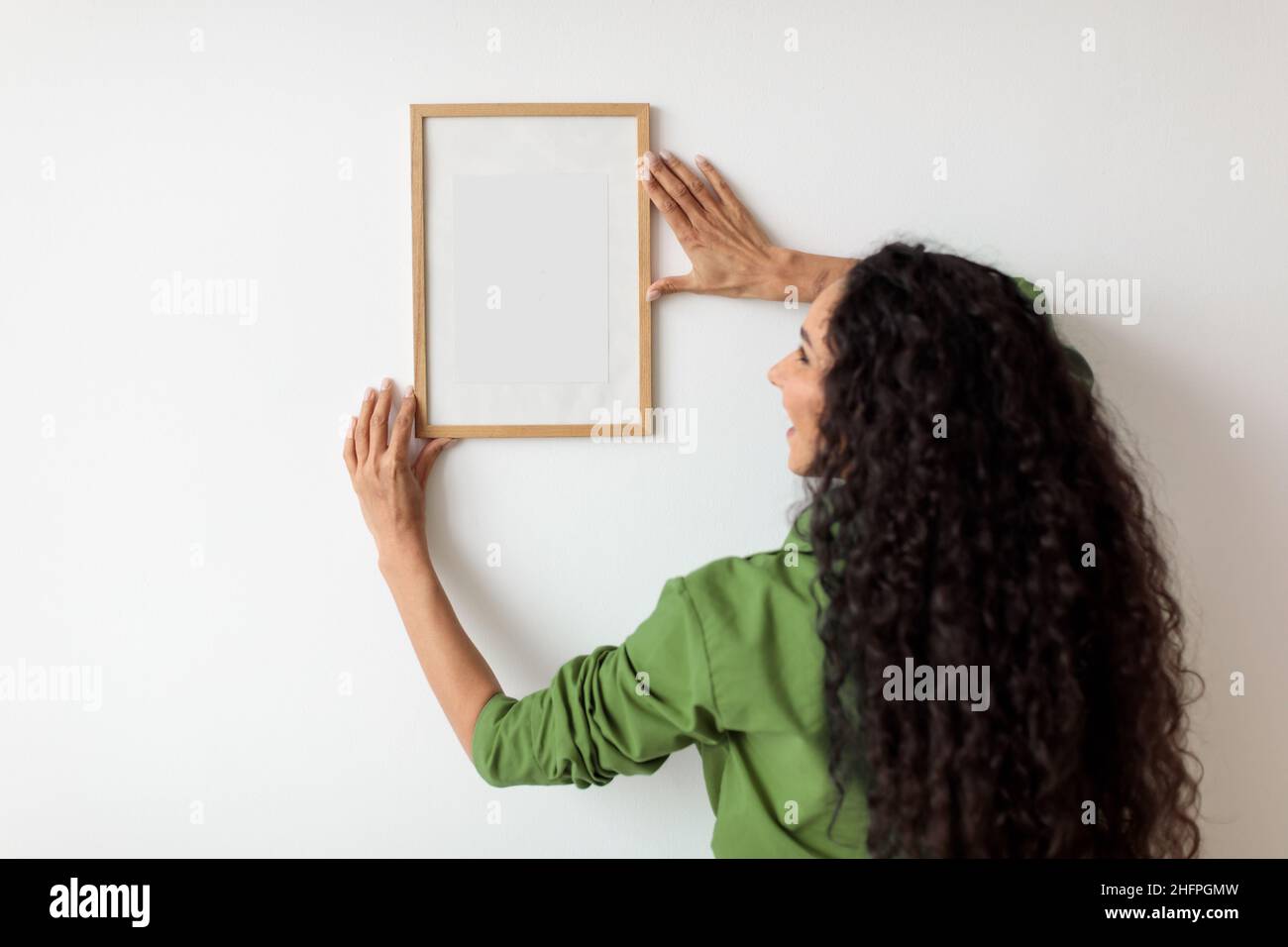 Female Hanging Empty Picture In Frame On White Wall Indoors Stock Photo