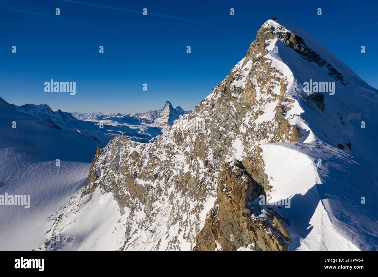 Dramatic aerial view of the Allalin peak and the Matterhorn in the background in the swiss alps in Canton Valais in Switzerland on a sunny winter day Stock Photo