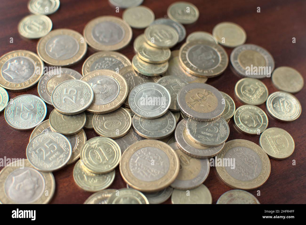 Some Turkish coins mixed on brown background. Some Turkish Liras on a brown table. Full of pocket of coins. Stock Photo