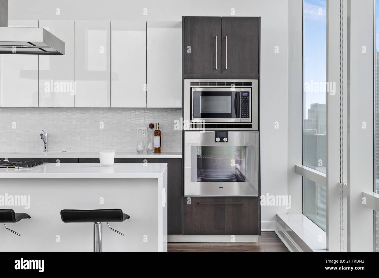 Luxury Penthouse Kitchen with City Views. Two Toned Cabinets with Waterfall Island and Stainless Steel Appliances. Modern and Contemporary Design. Stock Photo