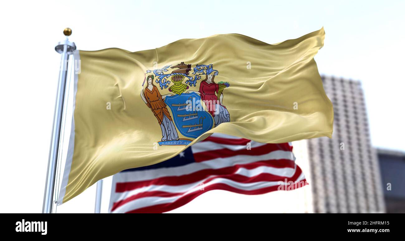 the flag of the US state of New Jersey waving in the wind with the American flag blurred in the background. New Jersey was admitted to the Union on De Stock Photo