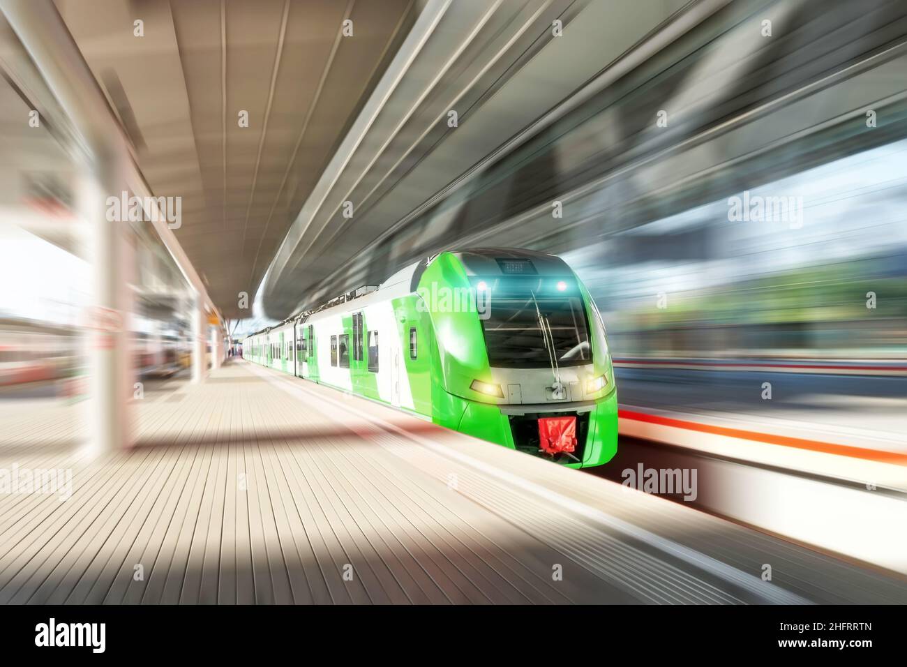 High speed train in motion on the railway station. Modern intercity passenger train with motion blur effect on the railway platform. Railroad commerci Stock Photo