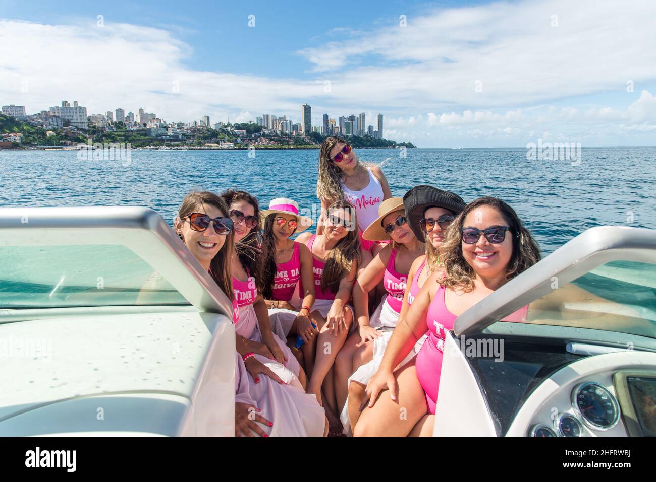Women in bikini sitting on a boat wearing pink outfit. Salvador, Bahia