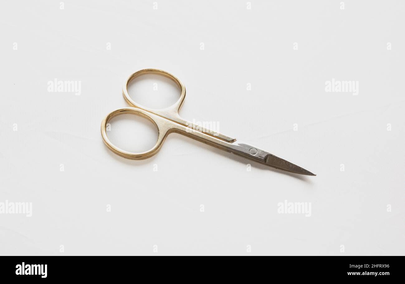 Small scissors. Steel nail scissors, gold hundle isolated on white background, design element. Stock Photo