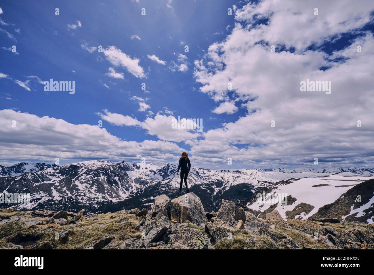 Young woman standing on boulder at altitude in the Rocky Mountains Stock Photo