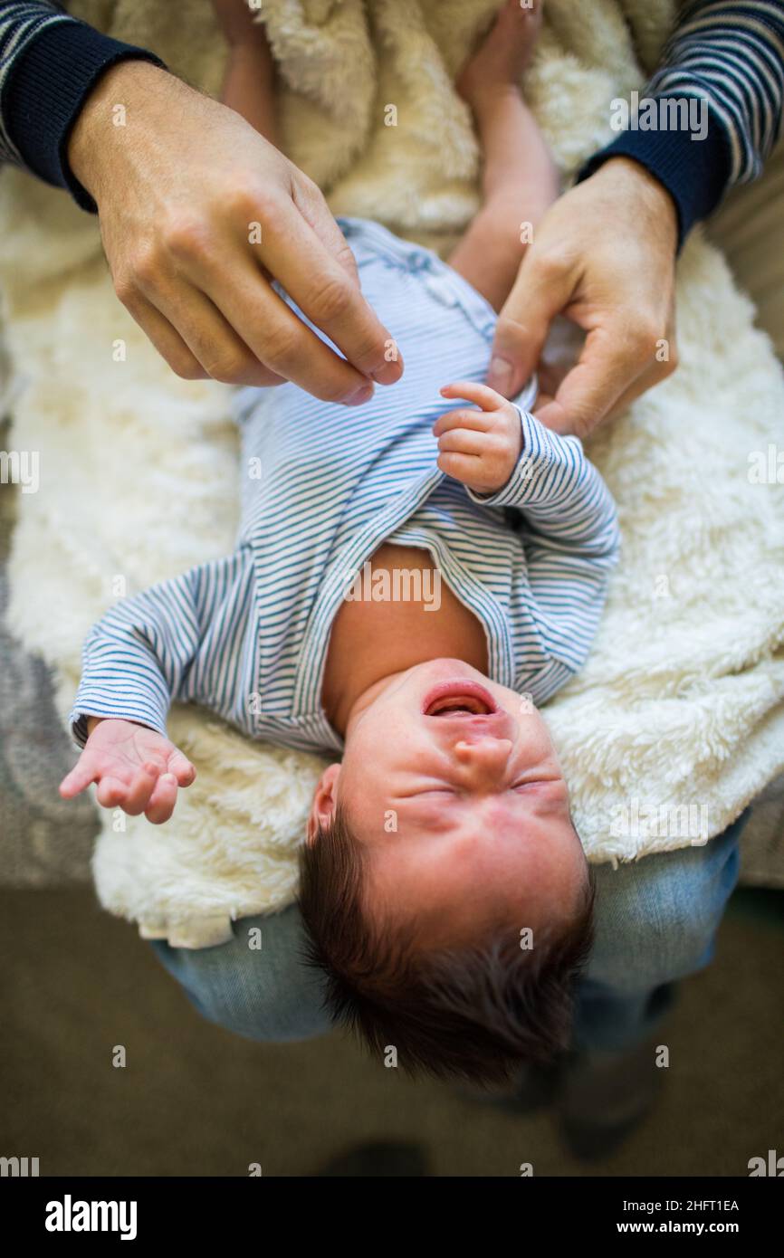 Detail of father dressing his son in blue clothing. Stock Photo