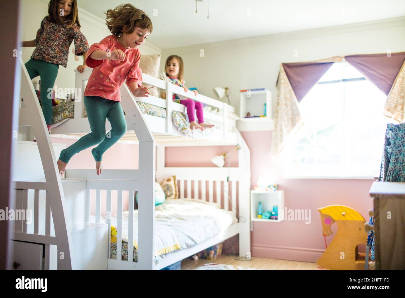 Young girls having fun, playing, jumping off bunk bed in bedroom Stock