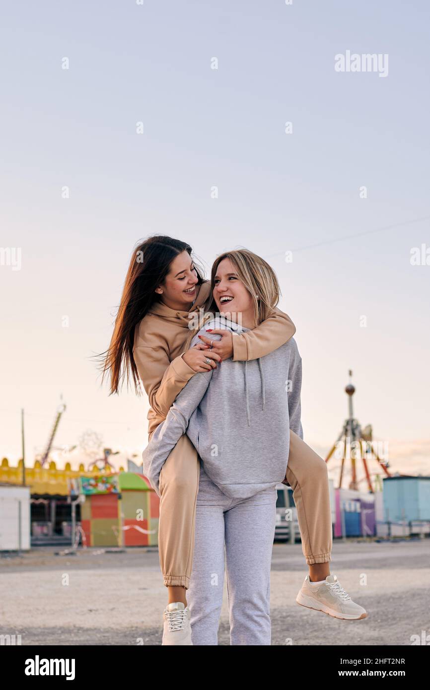Two women friends have a good time at a funfair at sunset Stock Photo