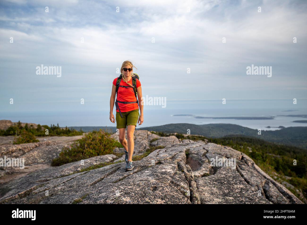 Fit woman hikes along summit of mountain, Acadia National Park, Maine Stock Photo