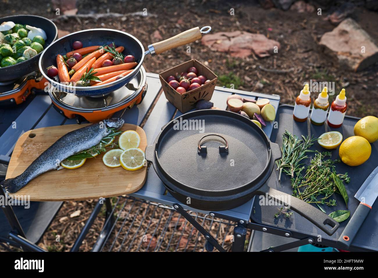 preparing camp dinner with herb stuffed trout and vegetables Stock