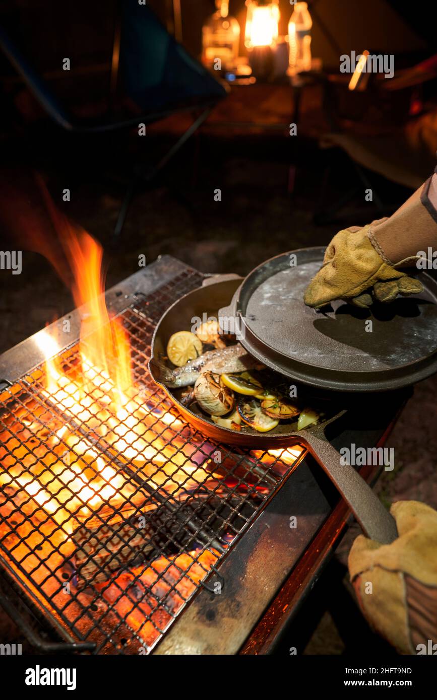 Male hands cooking in a cast-iron over an open fire. Stock Photo