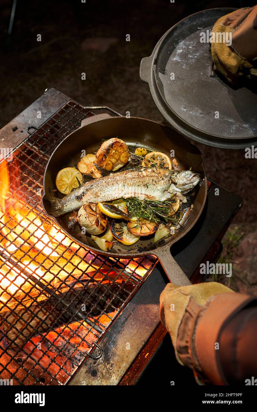 Chef cooking trout in a cast iron over an open fire. Stock Photo