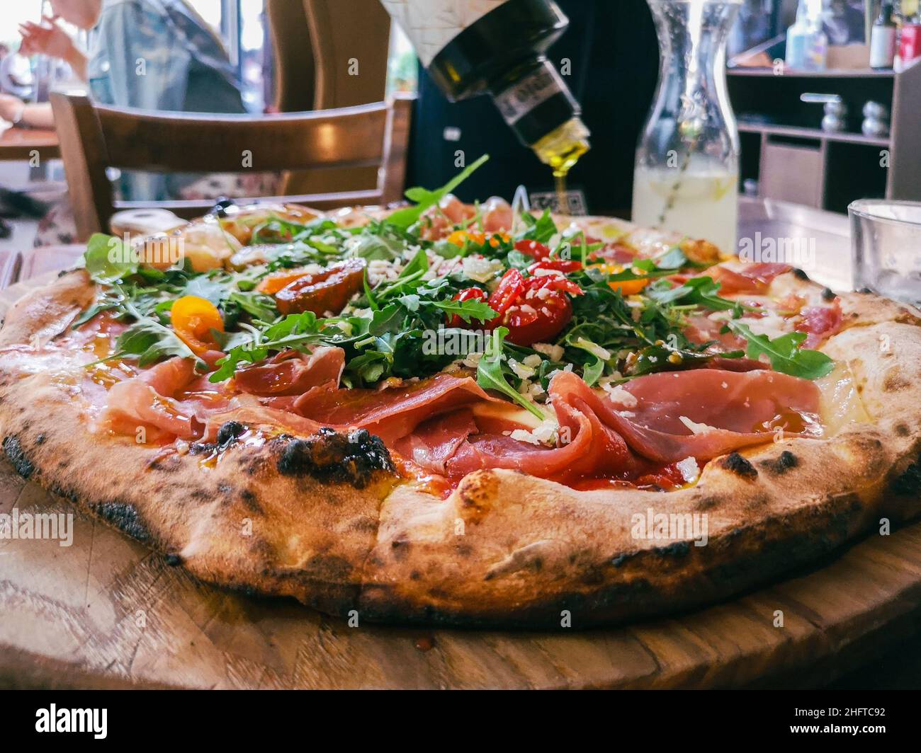 Close-up view of pouring olive oil on a pizza in a cafÃ© Stock Photo