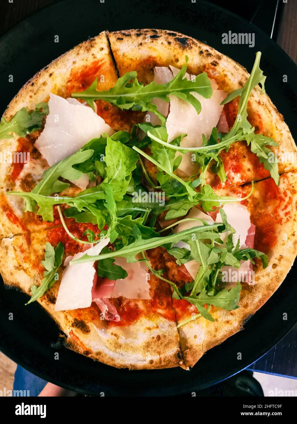 Top view of pizza with fresh Parmesan and arugula cut into four pieces Stock Photo