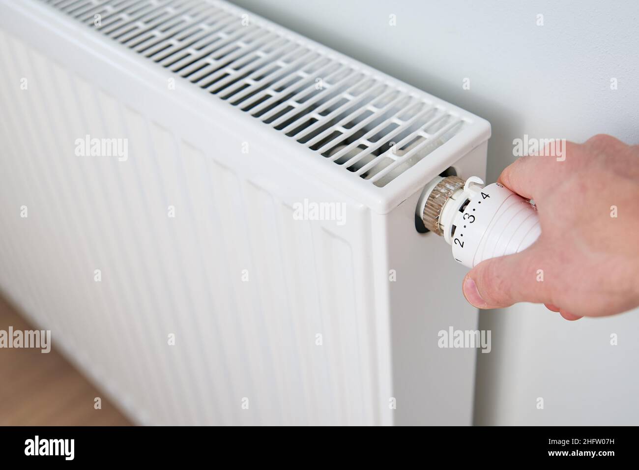Hand adjusting temperature on heating radiator thermostat, Turning heat radiator knob to control