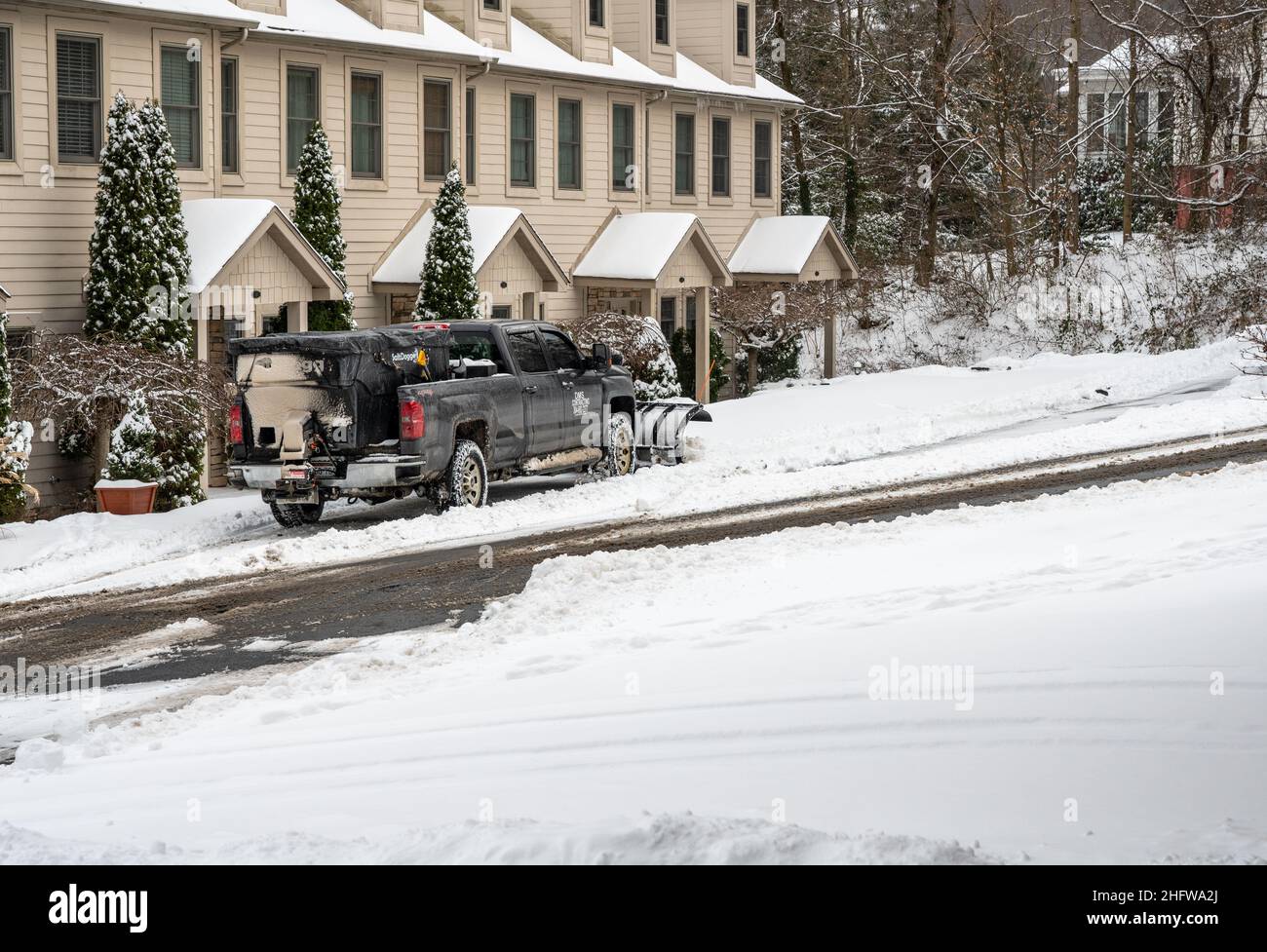 Morgantown, WV - 17 January 2022: Truck with snow plow blade attachment clearing residential street after snow storm Stock Photo