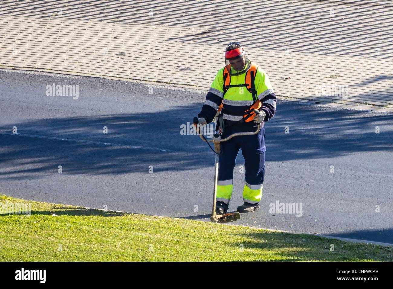 workers mowing lawn with grass trimmer outdoors on sunny day Stock Photo