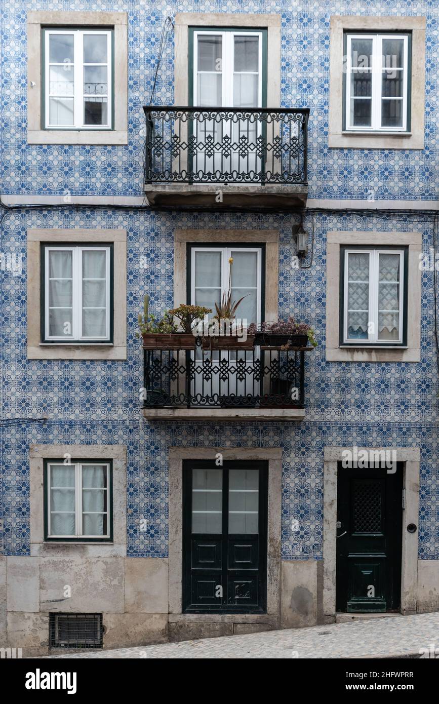 Architectural detail close-up of traditional blue tile wall facade of apartment building with cast iron railing balconies and flower boxes in Lisbon P Stock Photo