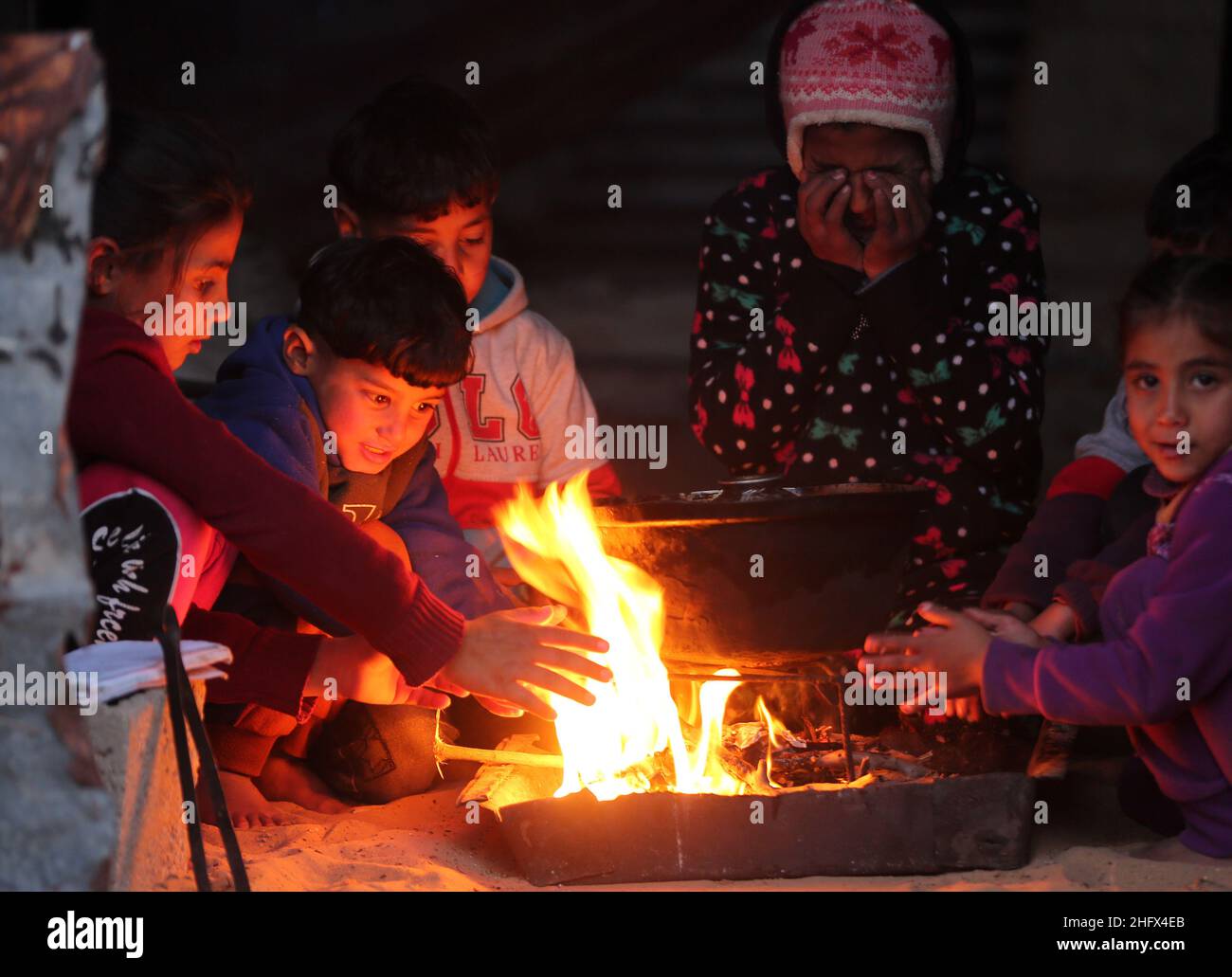 Gaza. 17th Jan, 2022. Members of a Palestinian family sit around a fire ...