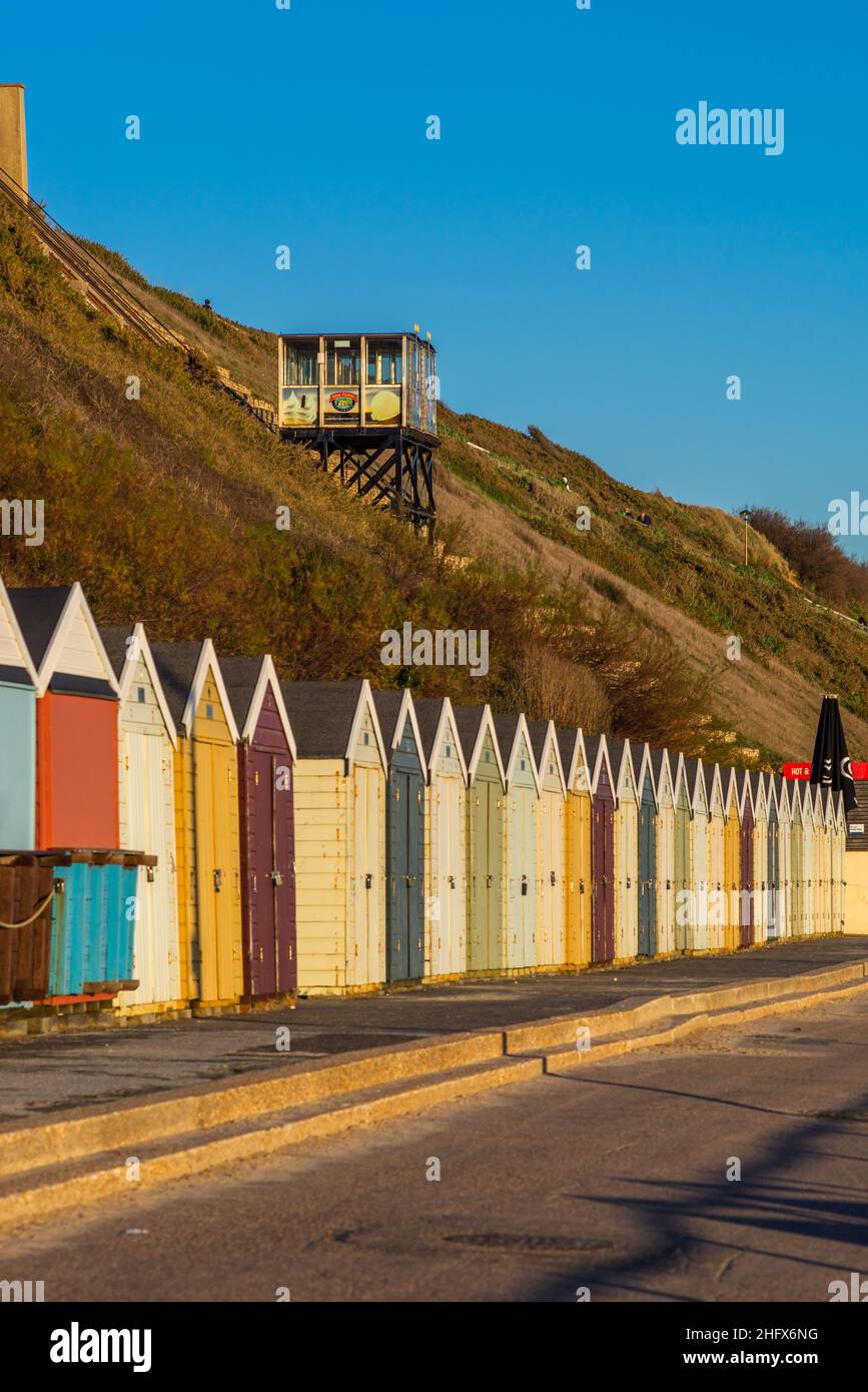 Colourful beach huts on Fisherman's walk in Boscombe with the famous cliff lift in the background, Southbourne Beach, Bournemouth, Dorset, England, UK Stock Photo