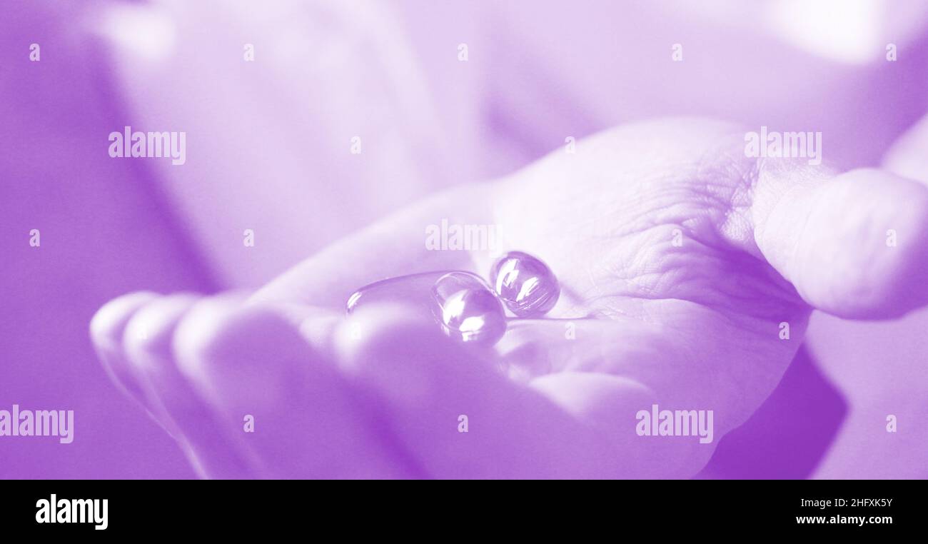 Soft gels pills with Omega-3 oil spilling out of pill bottle close-up iin aged woman hand. Healthcare concept . Selective foocus. Stock Photo