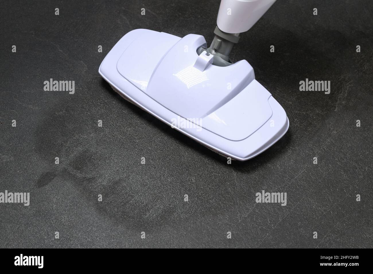 A man washes black porcelain stoneware with a steam mop. Killing germs, clean floor