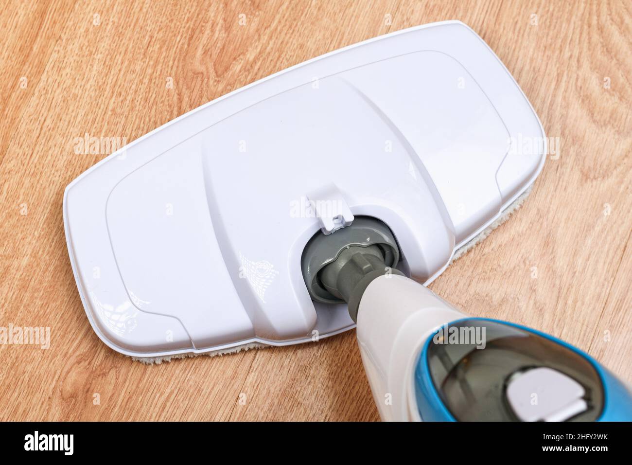 A man washes laminate flooring with a steam mop. Killing germs, clean floor, decontamination