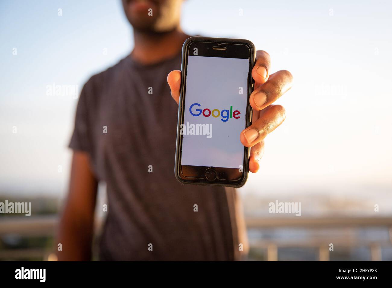 A man holds a smart sphone with the Google logo on the screen. Google is an American multinational technology company that specializes in Internet Stock Photo