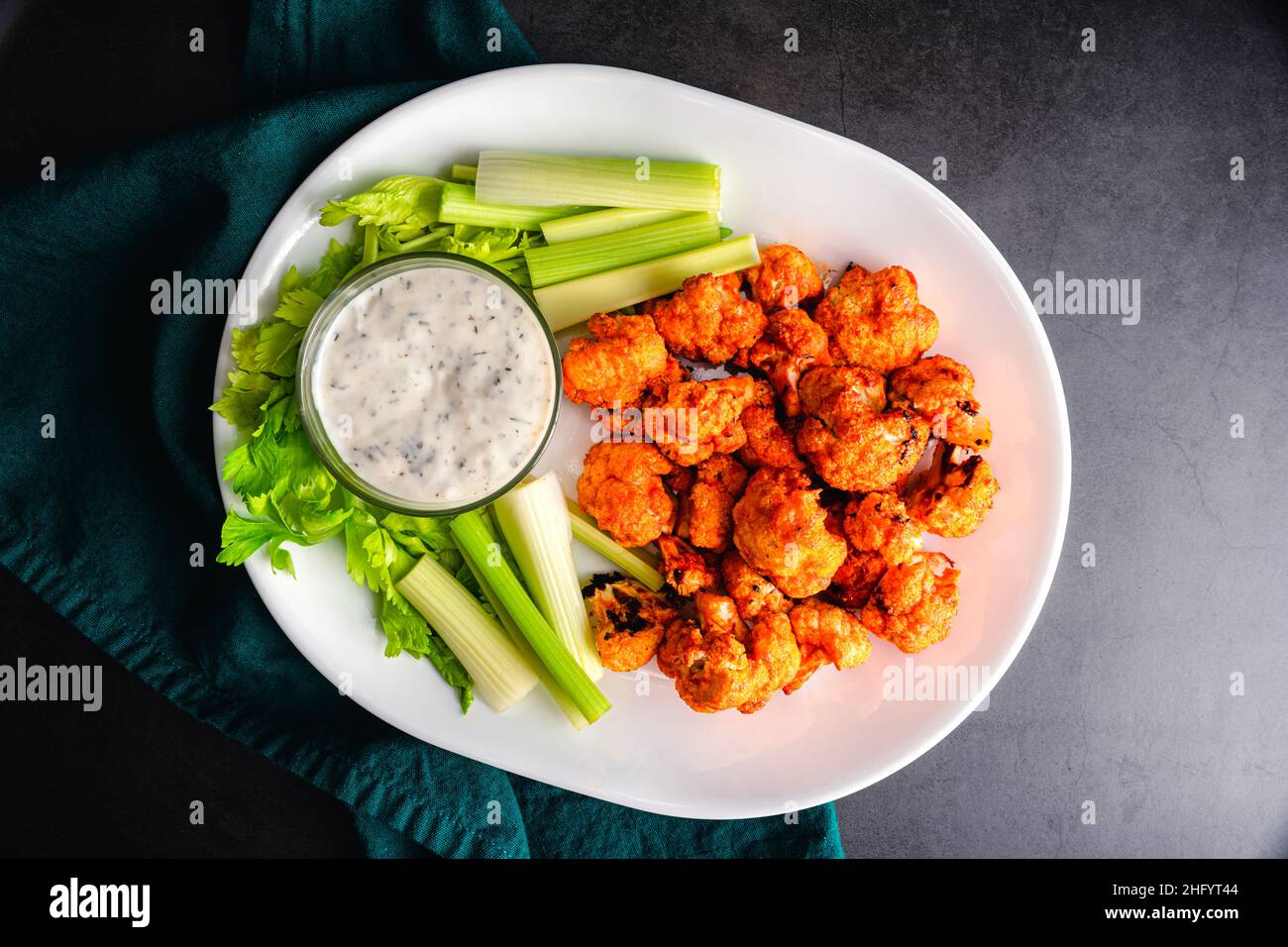 Buffalo Cauliflower Bites Served with Celery Sticks and Ranch Dressing: Vegetarian snack foods served on a white platter with dipping sauce Stock Photo