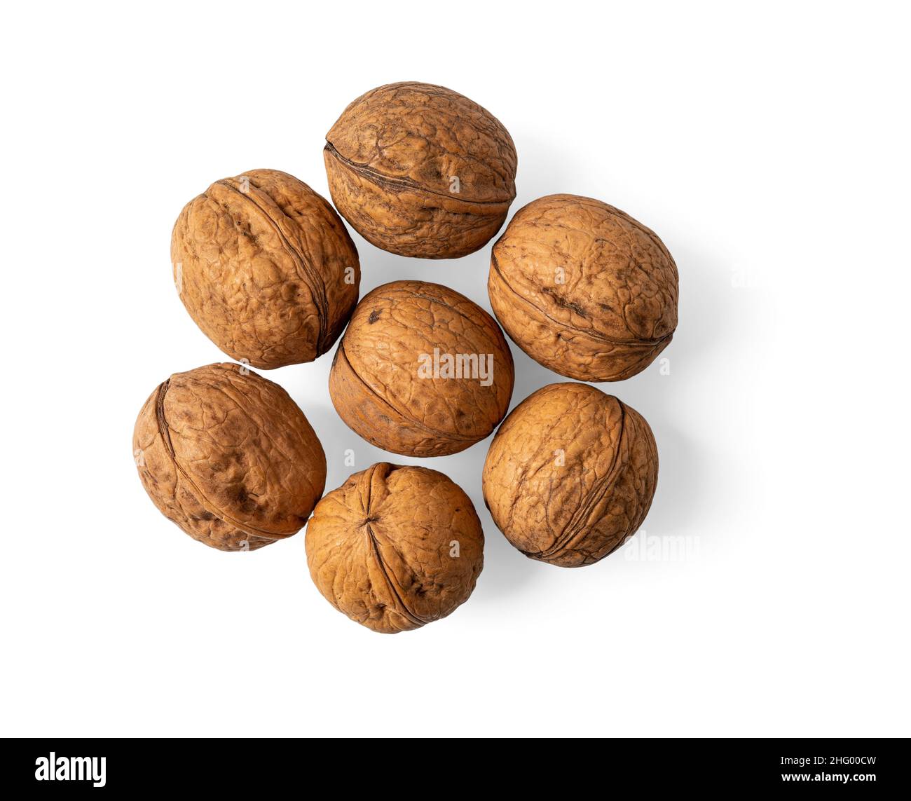 Unshelled walnuts heap isolated on a white background. Juglans regia tree fresh tasty fruits macro. Whole nuts in their shells cutout. Vegetarian food Stock Photo